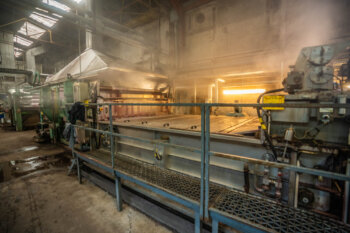 Machine de vaporisage en fonctionnement dans un atelier textile, diffusant une fine brume de vapeur sur le tissu pour fixer les couleurs et sublimer les motifs.