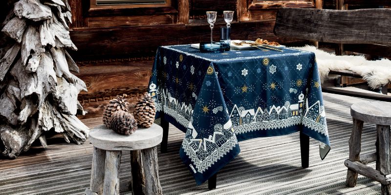 Nappe bleu Nuit étoilée dressée en extérieur près d'un chalet en bois. Ambiance chaleureuse et hivernale.