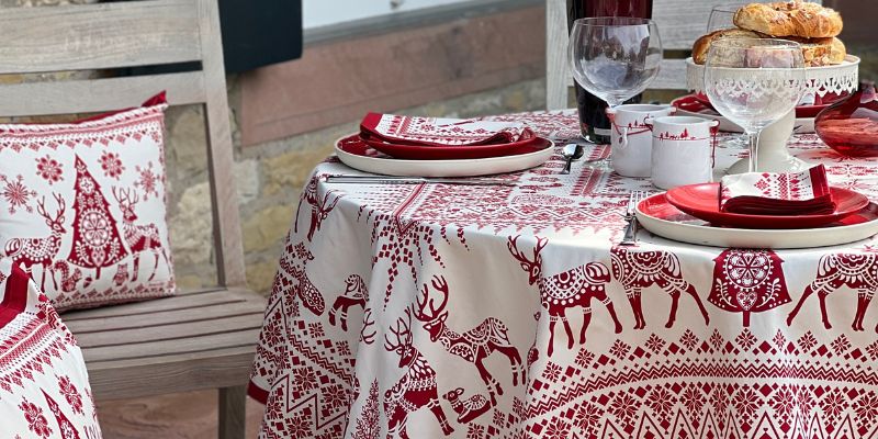 Nappe Balade en hiver ivoire/rouge mettant en avant les motifs forestiers. Table en extérieur gourmande et chaleureuse.