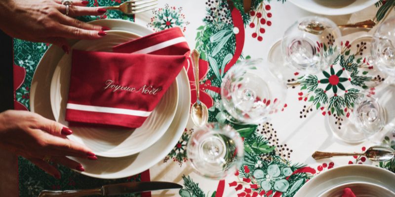 Serviette bicolore rouge et blanc personnalisée avec brodé Joyeux Noël disposée sur la nappe Réveillon.
