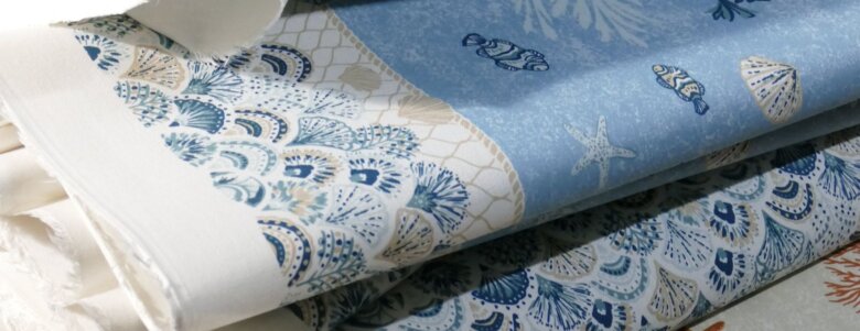 Empilement de tissus imprimés aux motifs marins bleus et beiges, inspiration océan et coquillages