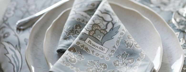 Serviette Parfum d’Orient givre pliée sur une assiette blanche