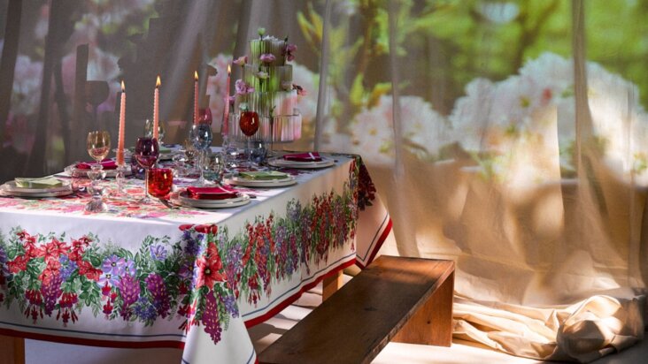 Nappe Beauvillé Bougainvilliers avec motif floral coloré sur une table dressée avec bougies et verres colorés, décor inspiré d’un jardin en fleurs.